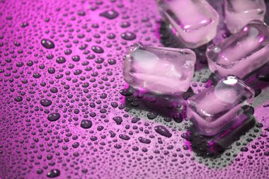 Karanlık bir zemin üzerinde su damlalarıyla şeffaf buzu eritmek.