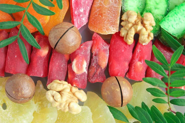 Candied fruits, dried fruits, macadamia nut, walnut, pineapple, dried apricots and olive leaves in macro form.