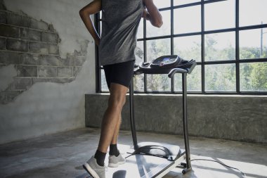 Yürüyen ve koşu bandında egzersiz yapan bir adam.