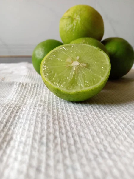 Fresh half cut juicy sour green lemon and white background — Stock Photo, Image