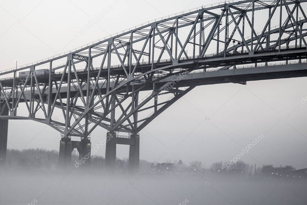 Urban Bridge In Fog Background. The International Blue Water Bridge in heavy fog. The Blue Water Bridges connect Port Huron, Michigan, USA and Sarnia, Ontario in Canada.