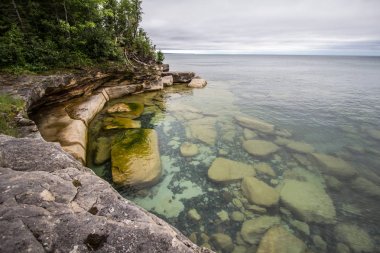 Cliffs On The Seashore. Rocky cliff on the shores of crystal waters of Lake Superior in Michigan's Upper Peninsula. clipart