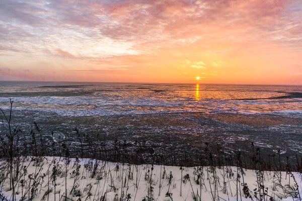 Scenic Winter Sunrise Landscape. Scenic sunrise reflection over the icy Great Lakes horizon on the coast of Lake Huron from an overlook in Port Sanilac, Michigan.