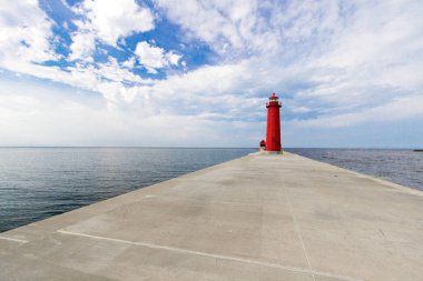 Kopya Boşluğu olan Kırmızı Deniz Feneri Arkaplanı. Kırmızı Grand Haven Deniz feneri, güneşli mavi gökyüzünün altında, uzun rıhtımı ve ön planda fotokopi alanı var..