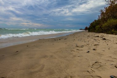 Stormy Beach geçmişleri. Fırtınalı gökyüzü ve Huron Gölü kıyısındaki Alpena Michigan yakınlarındaki Büyük Göller plajında dalgalar.. 