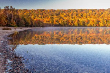 Autumn Lake Reflections. Vibrant fall colors reflected in the northern Michigan Monocle Lake at the Hiawatha National Forest in the Upper Peninsula of Michigan. clipart