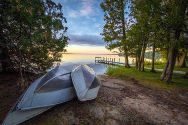 Sunset Gölü 'ndeki kayıklar. Günbatımı gölünün sahilinde, arka planda ahşap iskele olan bir grup alüminyum kayık. Hindistan Gölü Parkı, Manistique, Michigan, Usa.