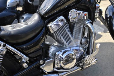 Yakın çekim motorsikletin ön tarafını gösteriyor. Sürücü koltuğu, gaz pedalı, motor, pil, anahtar kapağı, ayraç, egzoz borusu, sürücü ayaklığı ve şok emme için yay.