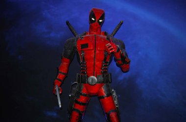 Chelyabinsk, Rusya - 17 Temmuz 2019. Kırmızı elbiseli ünlü bir süper kahraman elinde silah, arkasında kılıçlarla mavi arka planda duruyor ve gülümsüyor. Silahlar için bacaklara ve bel kemerlerine..