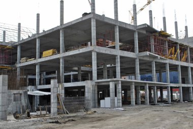 Çok katlı bina yavaş inşa ediliyor. Üçüncü katta inşaat malzemeleri var. Crane zemin inşa etmeye devam ediyor. Çatıda çalışan işçiler. Bina şekillenmeye başlıyor..