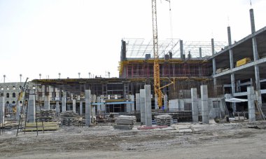 Çok katlı bina yavaş inşa ediliyor. Üçüncü katta inşaat malzemeleri var. Crane zemin inşa etmeye devam ediyor. Çatıda çalışan işçiler. Bina şekillenmeye başlıyor..