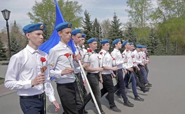 青いベレー帽と白いシャツを着た若い男たちは戦争で死んだ兵士たちに花を届けに行きます — ストック写真