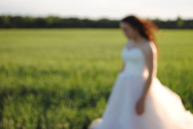 Tarladaki fotoğraf çekiminde gelin. Gelinin görünüşü. O, başını eğdi. Orman arka planda.