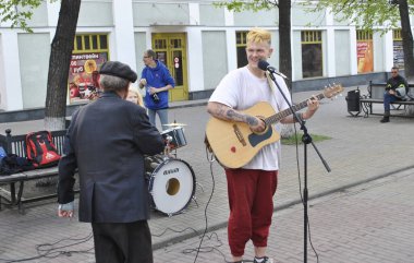 Chelyabinsk, Rusya - 10 Mayıs 2019. Yaşlı bir büyükbaba bir gösteri sırasında müzisyenlere yaklaşır. Adam davul çalar ve mikrofona şarkı söyler, kız da davul çalar..
