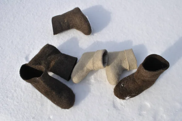 Three pairs of felt boots top view. White and brown shoes. Valenoks are covered with small ice floes. Snow stuck to the boots.