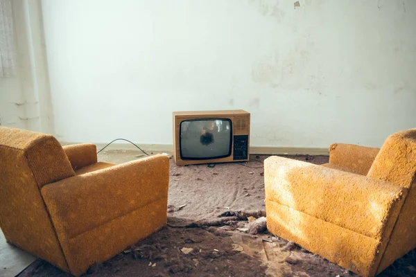 Kırık Tv önünde terkedilmiş kanepe sandalye çifti
