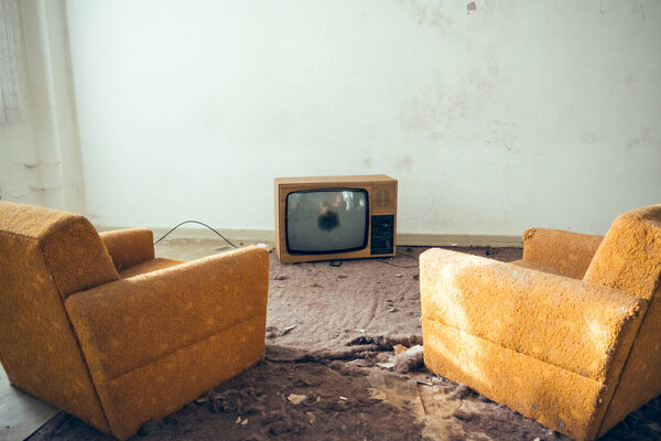 Пара неиспользуемых диванов перед сломанным телевизором
