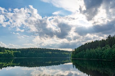 Mavi gökyüzü ve bulutlu orman gölü