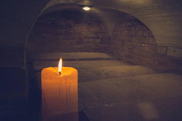 A candle in a dark old burial chamber — Stock Photo, Image