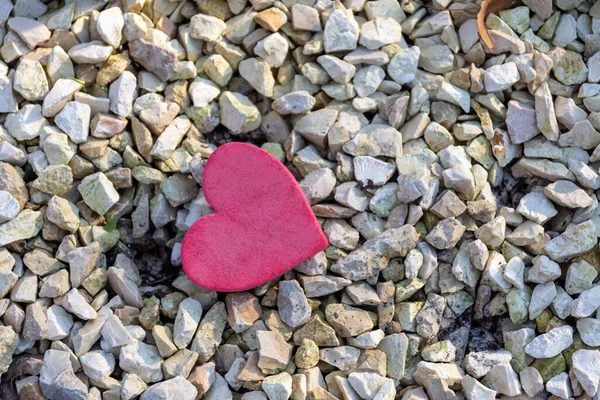 Een klein decoratief rood hart op stenen in de natuur — Stockfoto