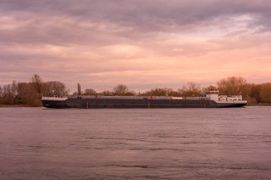 Almanya 'da günbatımında bir nehirde büyük bir kargo gemisi.