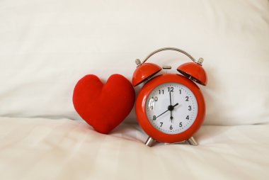 Kırmızı alarm saati ve kalp şekli üzerinde beyaz çarşaf