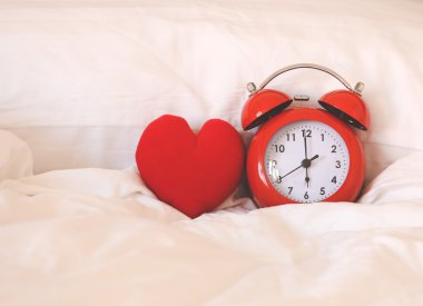 Kırmızı alarm saati ve kalp şekli üzerinde beyaz çarşaf