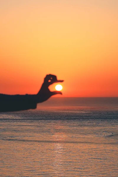 Силуэт руки, держащей солнце на закате — стоковое фото