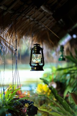 Yeşil bitkiler ile bambu çatıda eski petrol fener asmak