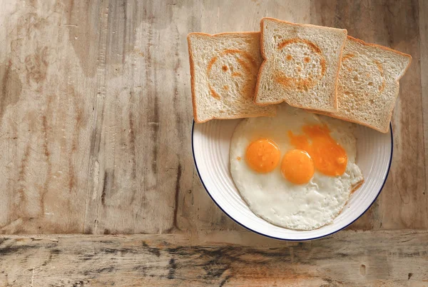 Wheat bread toasts with smiling stamp and fried eggs