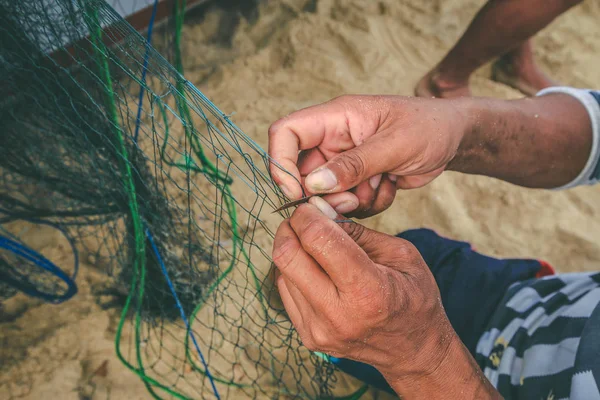 Рука рыбака, чинит рыболовные сети — стоковое фото