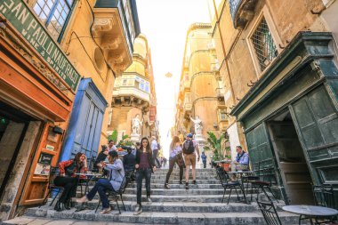 Valletta Malta - 1 Nisan 2018: Dar Sokağı, Valletta, Malta'nın merdivenlerde tablolarla küçük kafe. Tahıl doku stil uygulama 