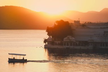 Udaipur 'daki Pichola Gölü' ndeki Taj Gölü Sarayı 'nda sabah güneş doğuyor.