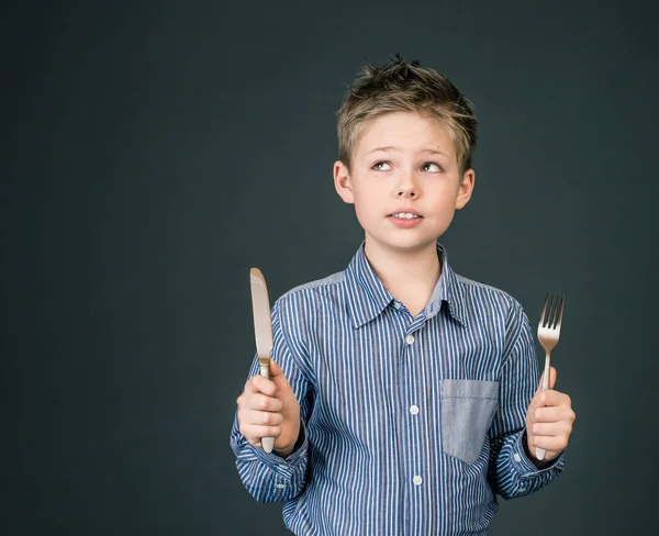 Liten pojke med gaffel och kniv. Hungriga barn. — Stockfoto