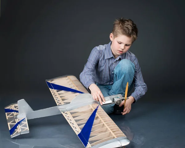 Pre-teen boy holding a wooden plane model. Kid playing with real — Stock Photo, Image