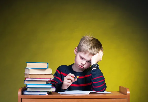 不快乐的累小男孩做他的作业。无聊的学校学习。教育理念. 图库图片