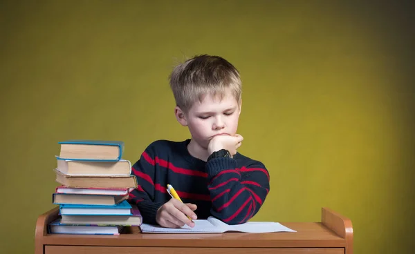不快乐的累小男孩做他的作业。无聊的学校研究 图库图片