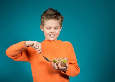 Sevimli çocuk üzerinde mavi arka plan izole tahıl yemek.