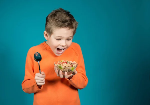 Leuke jongen eten granen geïsoleerd op blauwe achtergrond. — Stockfoto