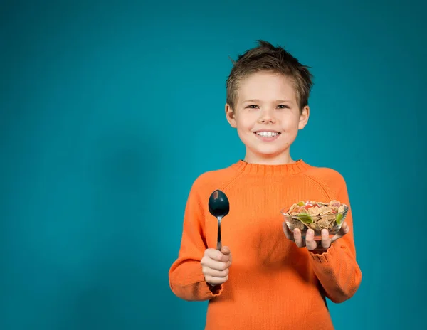 Söt pojke äter spannmål isolerad på blå bakgrund. — Stockfoto