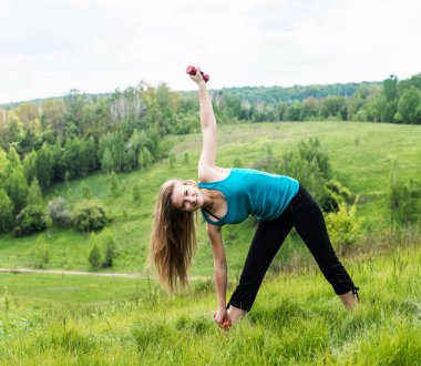 Fitness Egzersiz fitness gücü eğitim egzersiz çimenlerin üzerinde halter kullanan kadın. Yeşil park küçük ağırlıkları ile egzersiz eğitmen