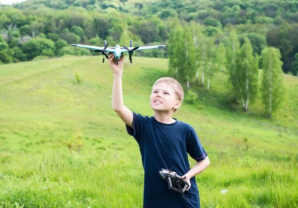 飞机草在晴朗的一天的快乐男孩。微笑准备推出 Rc 飞机的小男孩. 图库图片