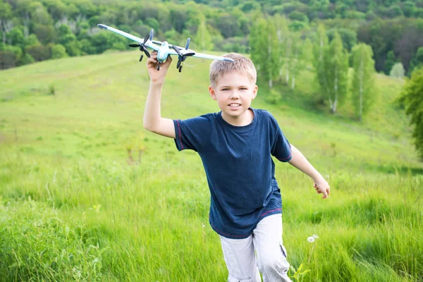 Happy kid playing with toy airplane against beautiful nature background. — Stock Photo, Image