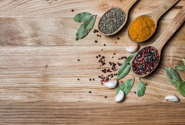 Baharat ve otlar. Ahşap zemin üzerine kaşık baharat. Köri, zerdeçal, fesleğen, karabiber ve diğer ahşap arka plan üzerinde. Yemek pişirmek için çeşitli baharatlar.