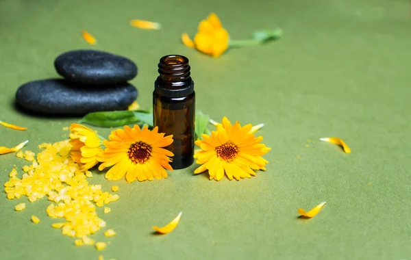 Essential aroma oil with calendula on green background. Selective focus. — Stock Photo, Image