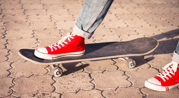 Benen in rode sneakers op een skateboard. Stockfoto