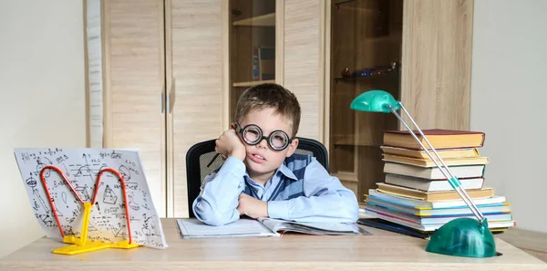 Müder Junge mit lustiger Brille bei den Hausaufgaben. Kind mit Lernschwierigkeiten — Stockfoto