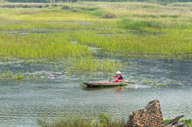 VANLONG NATURAL RESERVE, NINH BINH, VIETNAM - FEBRUARY 29, 2020:   An unidentified woman sailing  a boat on the lagoon. Due to Covid-19 impacts, very few tourists coming to the Reserve. 