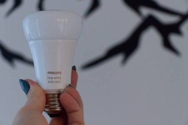 Vancouver, Kanada - 12 Ekim 2019: Bir kadın Philips Renk Ampulü 'nü arka planda beyaz bir duvarla elinde tutuyor