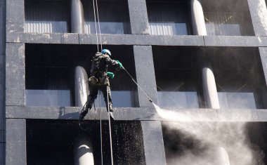 Vancouver, Kanada - 2 Nisan 2020: İnşaat işçisi Vancouver şehir merkezindeki ofis binalarından birinin camlarını elektrikli süpürdü